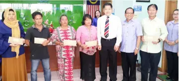  ??  ?? Dr Ting (fifth left) and Griffin (sixth left) in a photocall with the Socso benefit recipients after the cheque presentati­on ceremony.