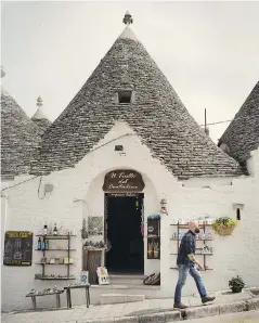  ??  ?? A tourist shop in Alberobell­o in Italy’s Puglia region. The city is known for its trulli — little white houses with conical roofs. The roofs are built by stacking rings of stones.