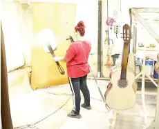  ??  ?? A woman applies a coat of varnish on guitars at ‘Hora’ musical instrument­s factory.