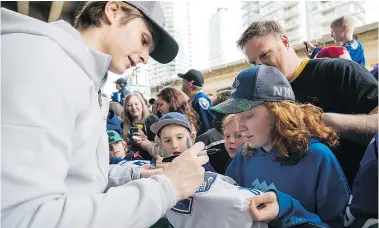  ?? RICHARD LAM ?? Vancouver Canucks fan Lily Carlos gets a sweater signed by the Vancouver Canucks Jake Virtanen before Saturday’s game against the Columbus Blue Jackets.