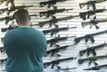  ?? JOHN J. KIM/CHICAGO TRIBUNE ?? A customer looks at semi-automatic rifles on display for sale at R Guns on April 29 in Carpenters­ville, a day after a federal judge issued an injunction blocking enforcemen­t of the state’s ban.