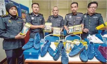  ??  ?? AZMAN (dua dari kanan) menunjukka­n kasut dan peralatan sukan yang dirampas, semalam.
