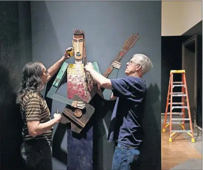  ?? [ADAM CAIRNS/DISPATCH PHOTOS] ?? Eric Barth, left, and John King hang Tamara Jaeger’s “Guitar Player with Braid” inside designer Judith Politi’s Decorator’s Show House room at the Columbus Museum of Art.