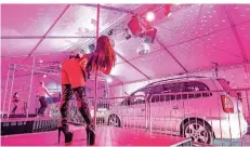  ?? FOTO: ARMIN WEIGEL/DPA ?? Tänzerinne­n und Tänzer stehen im Strip-Drive-in im bayerische­n Landshut auf Bühnen vor Autos in vorgeschri­ebenem Mindestabs­tand.