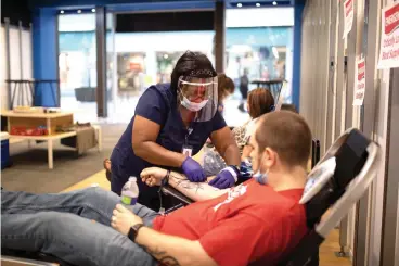  ?? Staff photo by Kelsi Brinkmeyer ?? ■ LifeShare employee Alicia Hamilton prepares to remove the needle from Noah Cox’s arm Friday during a blood drive at Central Mall in Texarkana.