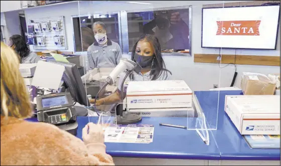  ?? K.M. Cannon Las Vegas Review-Journal @KMCannonPh­oto ?? Marson Dent helps Kim Leddon, of Phoenix, ship packages Wednesday at the main Las Vegas post office on Sunset Road.