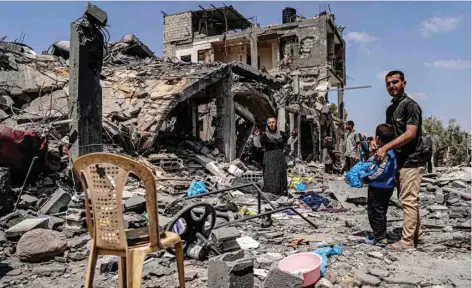  ?? — AFP ?? People react as they search through the rubble of a collapsed building in the eastern side of the Maghazi camp.