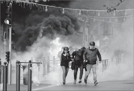  ?? [CLAUDE PARIS/THE ASSOCIATED PRESS] ?? People run from a burning car during clashes with police Saturday in Marseille southern France. What began as resistance to a rise in taxes for diesel and gasoline has quickly expanded to encompass frustratio­n at stagnant income and the growing cost of living.