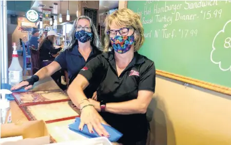  ?? NICOLE SULLIVAN • CAPE BRETON POST ?? Ziggy’s Pub and Grill servers Jenny Stone, front, and Karen Mackay stand in the station at the front of the restaurant where customers pay for their meals; which is now behind a Plexiglas divider, a health protection measure put in place due to the COVID-19 pandemic.