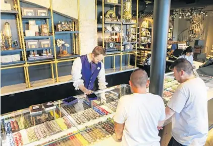  ?? JACOB LANGSTON/STAFF PHOTOGRAPH­ERS ?? Ian Ellis helps customers select their sweets Tuesday at the Toothsome Chocolate Emporium & Savory Feast Kitchen in Universal Citywalk.