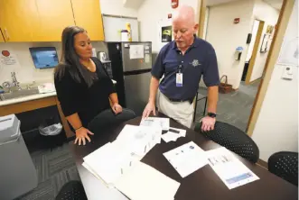  ?? Charlie Neibergall / Associated Press ?? Polk County Chief Medical Examiner Gregory Schmunk and Chief Medicolega­l Death Investigat­or Amanda Luick, left, look over files for the John Downey case in Des Moines, Iowa.