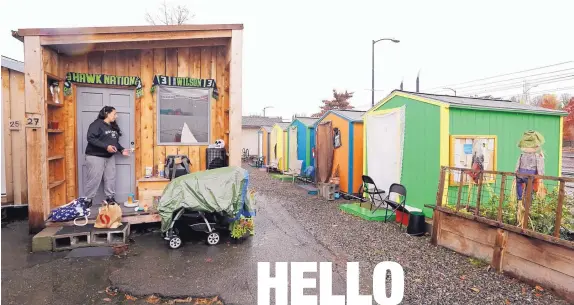  ?? AP PHOTO/ELAINE THOMPSON ?? Eva Stough opens the door to her tiny house, where she lives with her partner and baby, at a homeless encampment in Seattle. Tiny homes could be the solution to all kinds of housing needs, offering warmth and security for the homeless, an affordable...