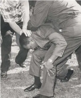  ?? SUN-TIMES FILE PHOTO ?? After being struck by a rock in Chicago’s Marquette Park neighborho­od during a 1966 open housing march, the Rev. Martin Luther King Jr. falls to one knee as fellow marchers come to his aid.