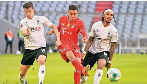  ?? FOTO: PETER KNEFFEL/AP ?? Mönchengla­dbachs Stefan Lainer (r.) und Valentino Lazaro versuchen, Bayerns Jamal Musiala zu stoppen.