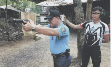  ?? PHOTO BY NELSON UYGONGCO ?? SPO2 Bobby Forro Ampatuan (left) trains his service firearm to top the proficienc­y firing tilt on May 19 as Phillipp Chua officiates.