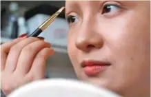  ??  ?? Makeup artist He Yuhong, also known as “Yuya”, applies makeup during a recording of her transforma­tion into the “Girl with a Pearl Earring”.