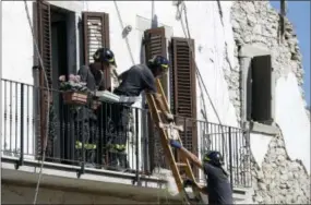  ?? THE ASSOCIATED PRESS ?? Firefighte­rs recover a crucifix and personal belongings Sunday from a damaged house in the village of Rio, Italy.