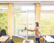  ?? FOTO: DANIEL BOCKWOLDT/DPA ?? Eine Schülerin öffnet mit einer Mund-Nasen-Bedeckung im Unterricht das Fenster, um das Klassenzim­mer zu lüften.