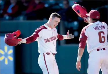  ?? NWA Democrat-Gazette/ANDY SHUPE ?? Arkansas freshman Casey Martin (left) accepts the Razorbacks’ home run hog hat from Hunter Wilson earlier this season. One of Arkansas’ superstiti­ons this season was to have the hog hat waiting at the plate after each home run.