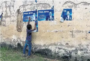  ?? AFP/GETTY IMAGES ?? Posters of Cameroonia­n President Paul Biya line a wall in the capital, Yaounde, on Tuesday.