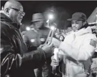  ??  ?? Activist Alvertis Simmons, far left, lights a candle as protesters gather by the Capitol in Denver. The group marched to protest the Ferguson, Mo., grand jury’s decision not to indict a police officer.