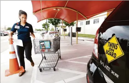  ?? Melissa Phillip photos / Houston Chronicle ?? 3. Nicole Cappelli, an H-E-B store manager, delivers a cart full of groceries to Leal, a 32-year-old mother of young twin daughters. Leal estimates the curbside-pickup service saves her 1½ hours per grocery trip. At least 10 other stores and...