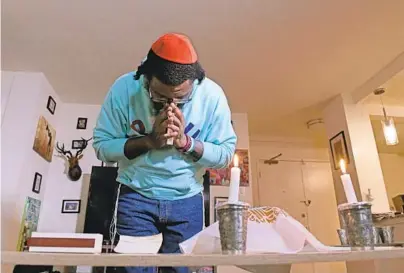  ?? KIM HAIRSTON/BALTIMORE SUN PHOTOS ?? KeSean Johnson recites Wednesday from the Tehillim, or Book of Psalms. Among items on the table are candles, challah and challah cover on a Passover Seder plate and cups of wine.