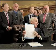  ?? Arkansas Democrat-Gazette/JOHN SYKES JR. ?? Gov. Asa Hutchinson holds up one of the two bills he signed Tuesday, one to raise fuel taxes and fees and to reallocate other resources to increase highway funding, and another to refer a constituti­onal amendment on the 2020 ballot to make permanent a half-percent sales tax for highway projects.