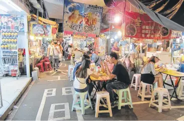  ?? Mai Pham photos ?? Young Taiwanese feast on street food at Raohe Night Market in Taipei.