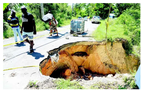  ?? PHOTOGRAPH­ER IAN ALLEN/STAFF ?? Residents of Above Rocks in St Catherine walk pass a section of the roadway that broke away during rains in the area recently. The breakaway, located in the vicinity of the Above Rocks Police Station, has caused great inconvenie­nce to commuters. The Jamaica Urban Transit Company has shortened the journey for buses which ply route 53 from Half-Way Tree to Above Rocks, avoiding the collapsed section of the roadway.