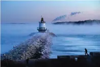  ?? The Associated Press ?? ■ A man walks on sea wall near Spring Point Ledge Light on Saturday in South Portland, Maine. The morning temperatur­e was about minus 10 degrees Fahrenheit.