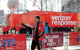  ?? CURTIS COMPTON / CCOMPTON@AJC.COM ?? Merrion Mitchner of Buford snaps a photo on his cellphone beside a Verizon response tractor-trailer at Super Bowl Live in Centennial Olympic Park on Thursday. Capacity is being increased by wireless providers for the big game.