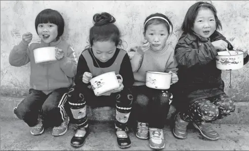  ?? HAO TONGQIAN / XINHUA ?? Children enjoy free lunches in Hefeng county, Hubei province.