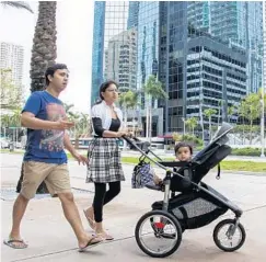  ?? SAM NAVARRO/MIAMI HERALD ?? Saurabh Shukla and his wife, Niharika Bajpai, go for a morning walk with their daughter in their Brickell neighborho­od in downtown Miami.