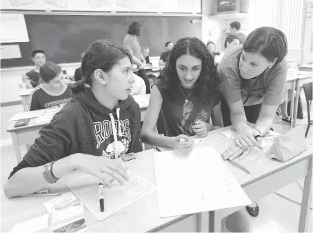  ?? JASON KRYK ?? Students Ella Yaung, left, and Mila Macera work with teacher Brianne Thomsich, right, during a Grade 9 applied math class at St. Thomas of Villanova Catholic High School in LaSalle on Wednesday.