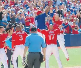  ?? Tom Szczerbows­ki Getty Images ?? STEVE PEARCE, right, arrives at the plate after hitting a walk-off slam for Toronto against the Angels. Pearce hit a walk-off slam Thursday against Oakland.