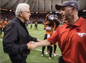  ?? The Canadian Press ?? B.C. Lions head coach Wally Buono, left, and Calgary Stampeders head coach Dave Dickenson shake hands after Buono coached his last regular season CFL game in Vancouver on Saturday.