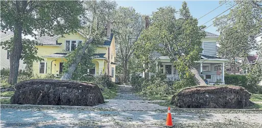  ?? ANDREW VAUGHAN PHOTOS THE CANADIAN PRESS ?? Large trees were seen uprooted throughout the Halifax region on Sunday, some resting on homes, as shown above, while others had pulled down power lines.
