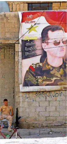  ?? FOTO: KARWASHAN/AFP ?? Alltag in Syrien: Ein Soldat wartet auf einen Konvoi aus dem Rebellenge­biet OstGhuta. Neben ihm ein Plakat des Machthaber­s Baschar al-Assad.