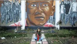  ?? Patrick Semansky Associated Press ?? JAZMIN Holloway sits below a mural of Freddie Gray at the intersecti­on where he was arrested in Baltimore. He suffered a spinal injury in a police van and died.