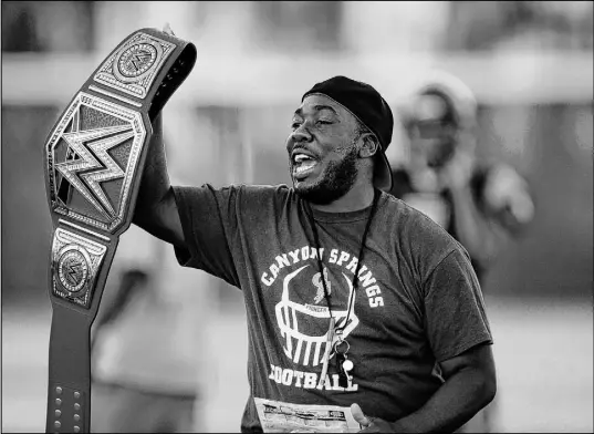  ?? Josh Holmberg Las Vegas Review-Journal ?? Canyon Springs coach Gus McNair, shown at practice in 2017 holding a WWE belt, said the Pioneers have “great confidence. The guys feel like they can compete and play at a high level.” Canyon Springs will open the playoffs against Arbor View on Friday.