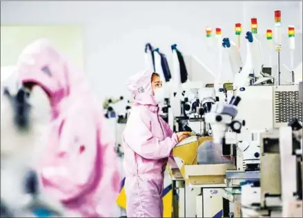  ?? AFP ?? Chinese employees wearing face masks and protective suits work on a smart chip production line in Sihong in China’s eastern Jiangsu province.