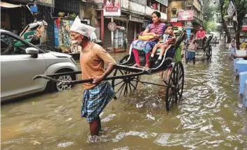  ?? PTI ?? A rickshaw-piller transports passengers across a waterlogge­d street in Kolkata, West Bengal, yesterday. Relative humidity reached 97 per cent yesterday.