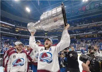  ?? PHELAN EBENHACK/ASSOCIATED PRESS ?? Colorado Avalanche center Nathan MacKinnon lifts the Stanley Cup after the team defeated the Tampa Bay Lightning in Game 6 of the Stanley Cup Finals on Sunday in Tampa, Fla.