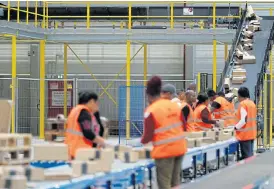  ?? /Reuters ?? Keep calm and carry on: Employees sort packages at the Amazon distributi­on centre warehouse in Saran, near Orleans, France. Monitoring and analysis of workers’ actions are growing.