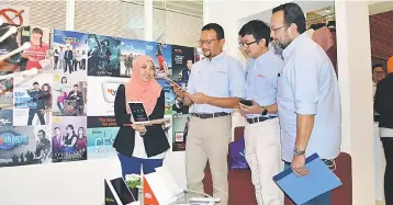  ??  ?? (From second left) Imri, Sarbini and Khaidir look at a tablet showcasing TM services at TM’s booth during the SME BizFest 2017 in Sarawak.