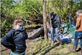  ?? JOSIE NORRIS/THE TENNESSEAN ?? Meredith Jaulin of Shower the People talks on the phone while surveying flood damage to an encampment of unhoused people adjacent to Nashville’s Caldwell Park on March 29.
