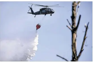  ?? PHOTOS BY RALPH BARRERA / AMERICAN-STATESMAN ?? A Texas National Guard helicopter drops water on troubled areas Sunday afternoon as local fire officials try to contain the Hidden Pines fire in Smithville. Residents in the fire zone have yet to be cleared to return to their homes as other evacuees started to return home Sunday.