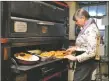  ?? ?? A Sugar Nymphs employee pulls food out of the oven on Sunday (Feb. 6).