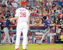  ?? Mark J. Terrill Associated Press ?? ANGELS PITCHER Jared Weaver looks on as Byron Buxton of the Twins, right, is congratula­ted by third base coach Gene Glynn after hitting a solo home run.